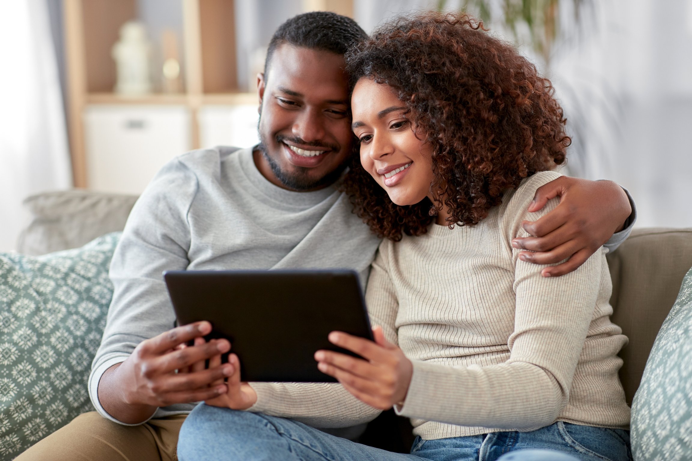 Couple Sitting on the Sofa Using Their Tablet Computer